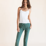 Model wearing Women's Lounge Pants in Pine under white camisole on a beige background