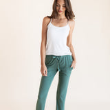 Model wearing Women's Lounge Pants in Pine under white camisole on a beige background