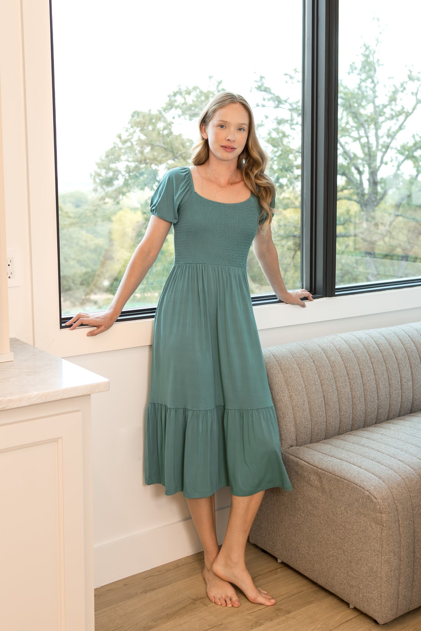 Woman modeling a smocked midi dress in a muted sage green in a living room
::: Model is 5'10" wearing size S ///