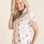Model smiling in Women's Short Sleeve Cropped Pajama Set in Pumpkin Spice Latte print on a beige background