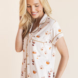 Model smiling in Women's Short Sleeve Cropped Pajama Set in Pumpkin Spice Latte print on a beige background