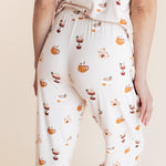 Model showcasing the backside of Women's Short Sleeve Cropped Pajama Set in Pumpkin Spice Latte print on a beige background