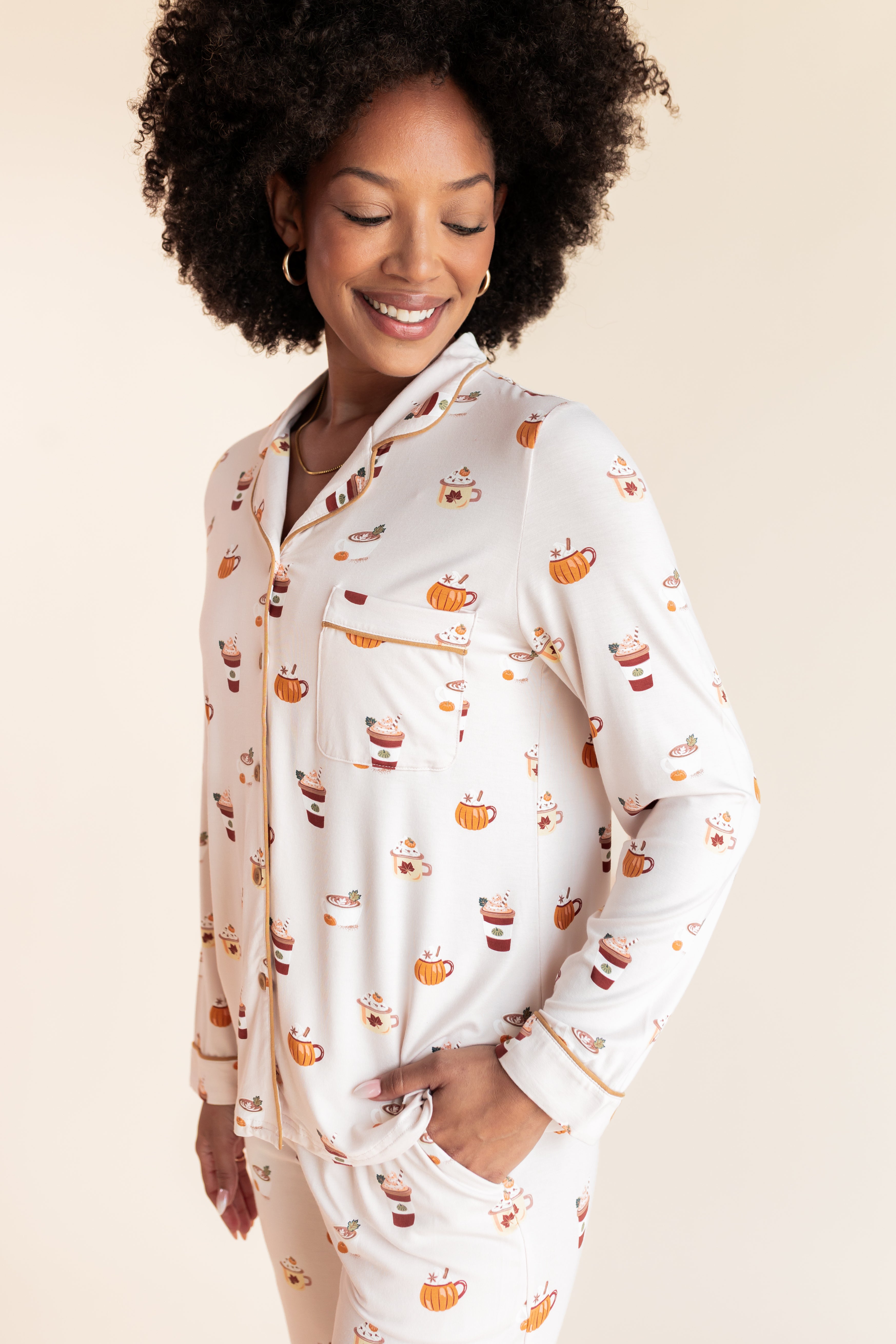 Close up of Model wearing Long-Sleeved Women's Pajama Set in Pumpkin Spice Latte print on a beige background