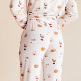 Model showcasing the Back side of Long-Sleeved Women's Pajama Set in Pumpkin Spice Latte print on a beige background