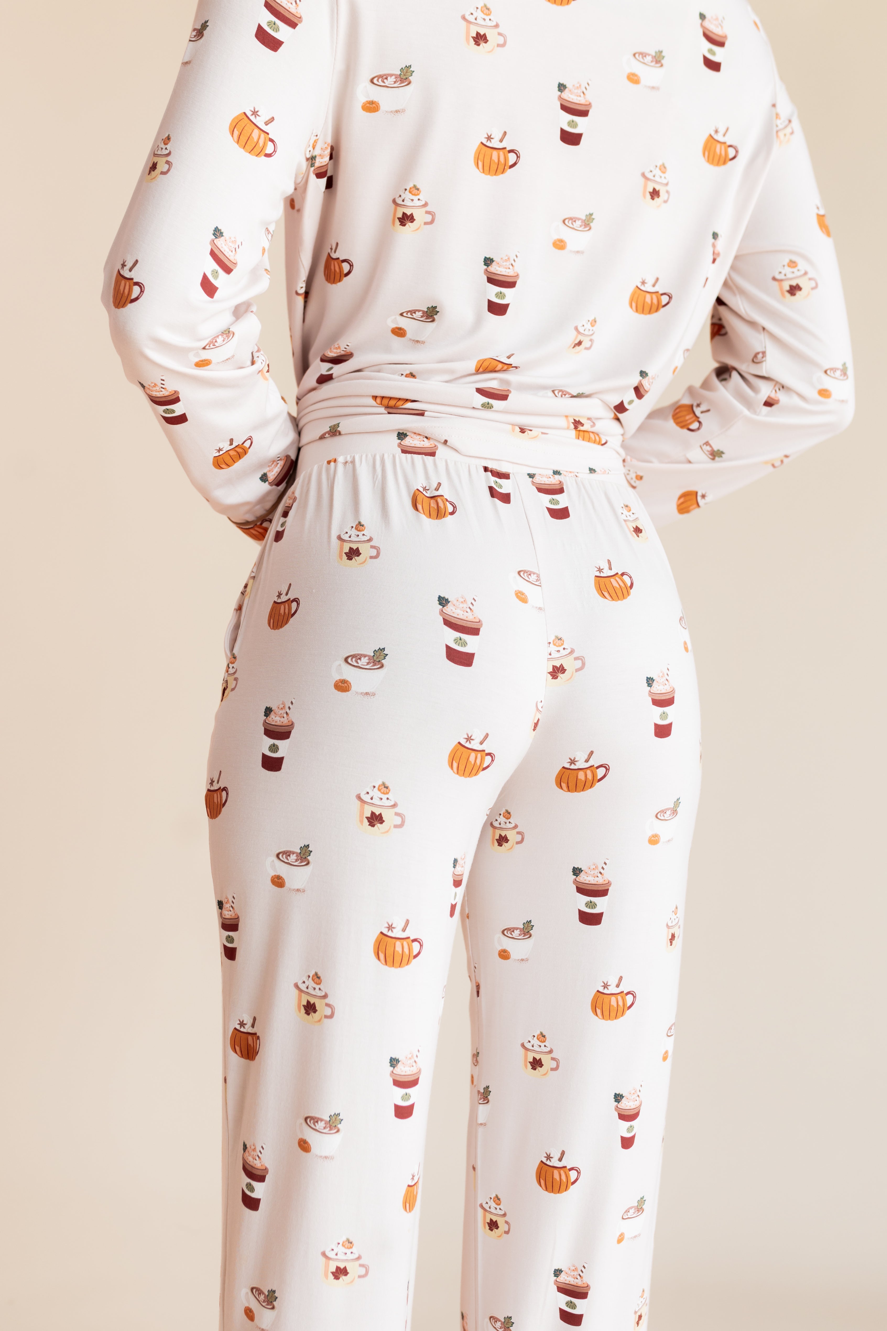 Model showcasing the Back side of Long-Sleeved Women's Pajama Set in Pumpkin Spice Latte print on a beige background