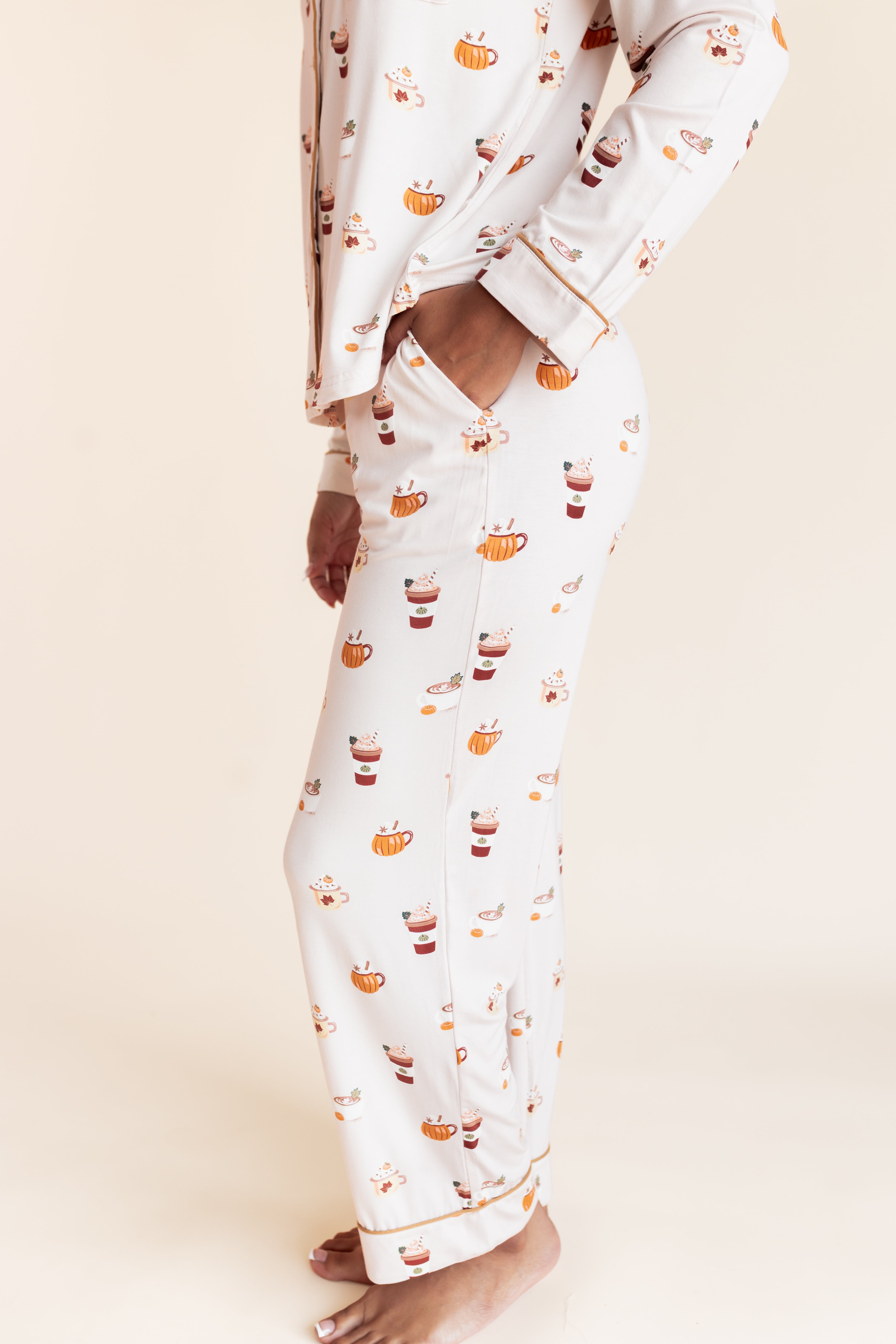 Model showcasing pockets on Long-Sleeved Women's Pajama Set in Pumpkin Spice Latte print on a beige background