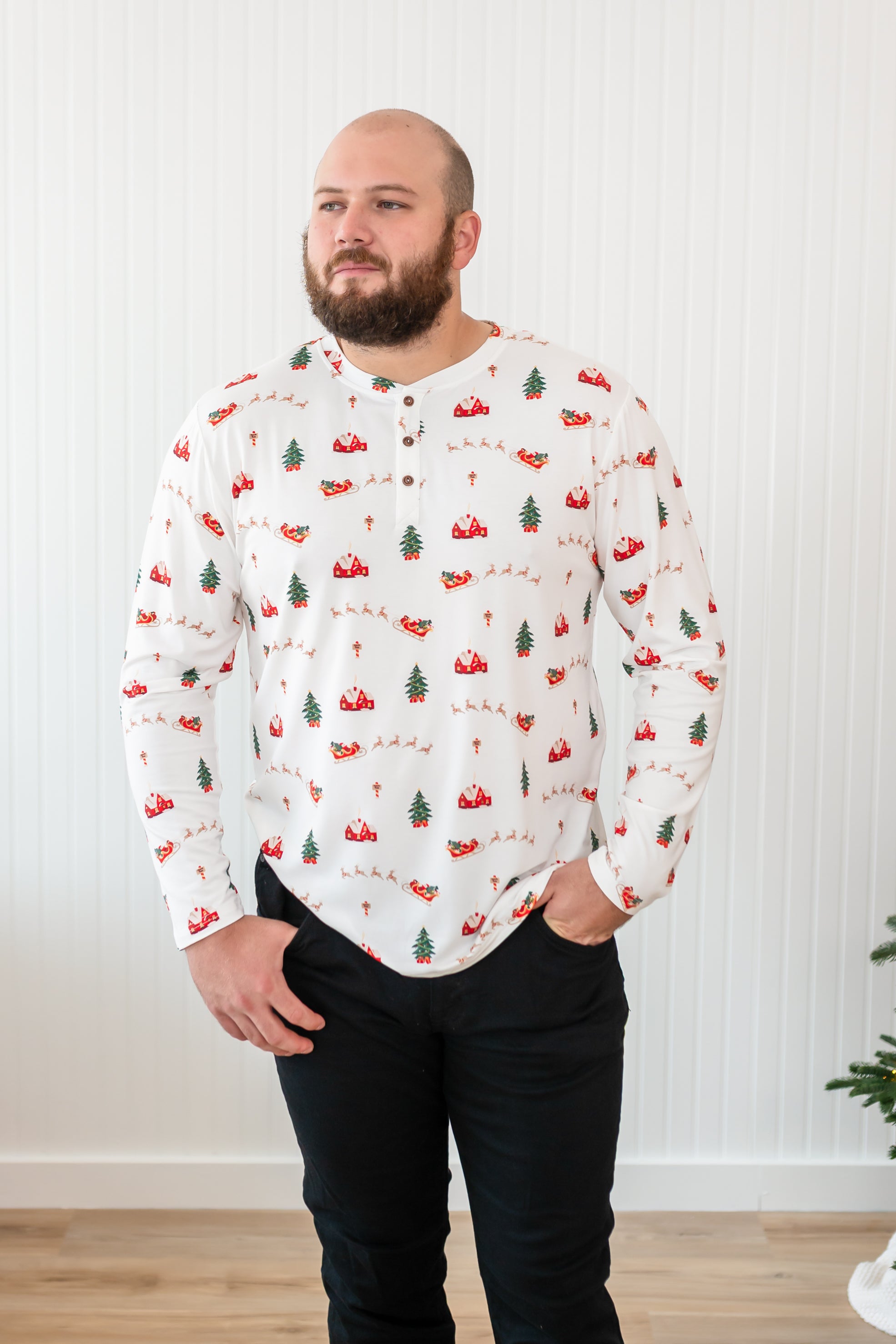 Male model looking to the side while wearing the Kyte Men's Long Sleeve Henley Top in Santa Sleigh