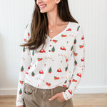 Model looking to the side with her hand in her pocket while wearing the Kyte Women's Long Sleeve Henley Tee in Santa Sleigh