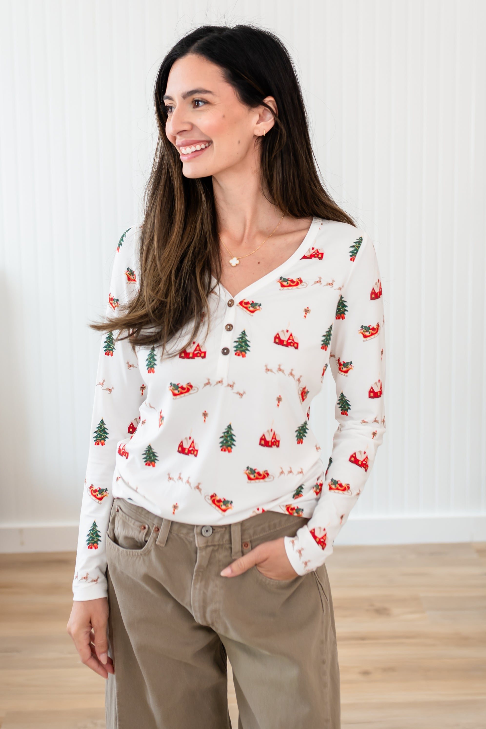 Model looking to the side with her hand in her pocket while wearing the Kyte Women's Long Sleeve Henley Tee in Santa Sleigh