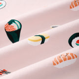 A close-up of a pink fabric with a repeating sushi print, including nigiri, maki, and sashimi motifs in yellow, green, orange, and white.---1615 1