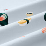 A close-up of a light blue-gray fabric with a repeating sushi print, including nigiri, maki, and sashimi motifs in yellow, green, orange, and white.---1615 1