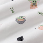Close up of the bamboo fabric: A repeating, all-over print featuring Grogu in a hover pram; a dark grey Mandalorian helmet; Grogu holding a grey cup; Grogu with his eyes closed, telekinetically manipulating a small silver ball; and leaping green Arges Frogs with black stripes, over a white background.