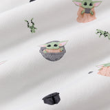 Close up of the bamboo fabric: A repeating, all-over print featuring Grogu in a hover pram; a dark grey Mandalorian helmet; Grogu holding a grey cup; Grogu with his eyes closed, telekinetically manipulating a small silver ball; and leaping green Arges Frogs with black stripes, over a white background.