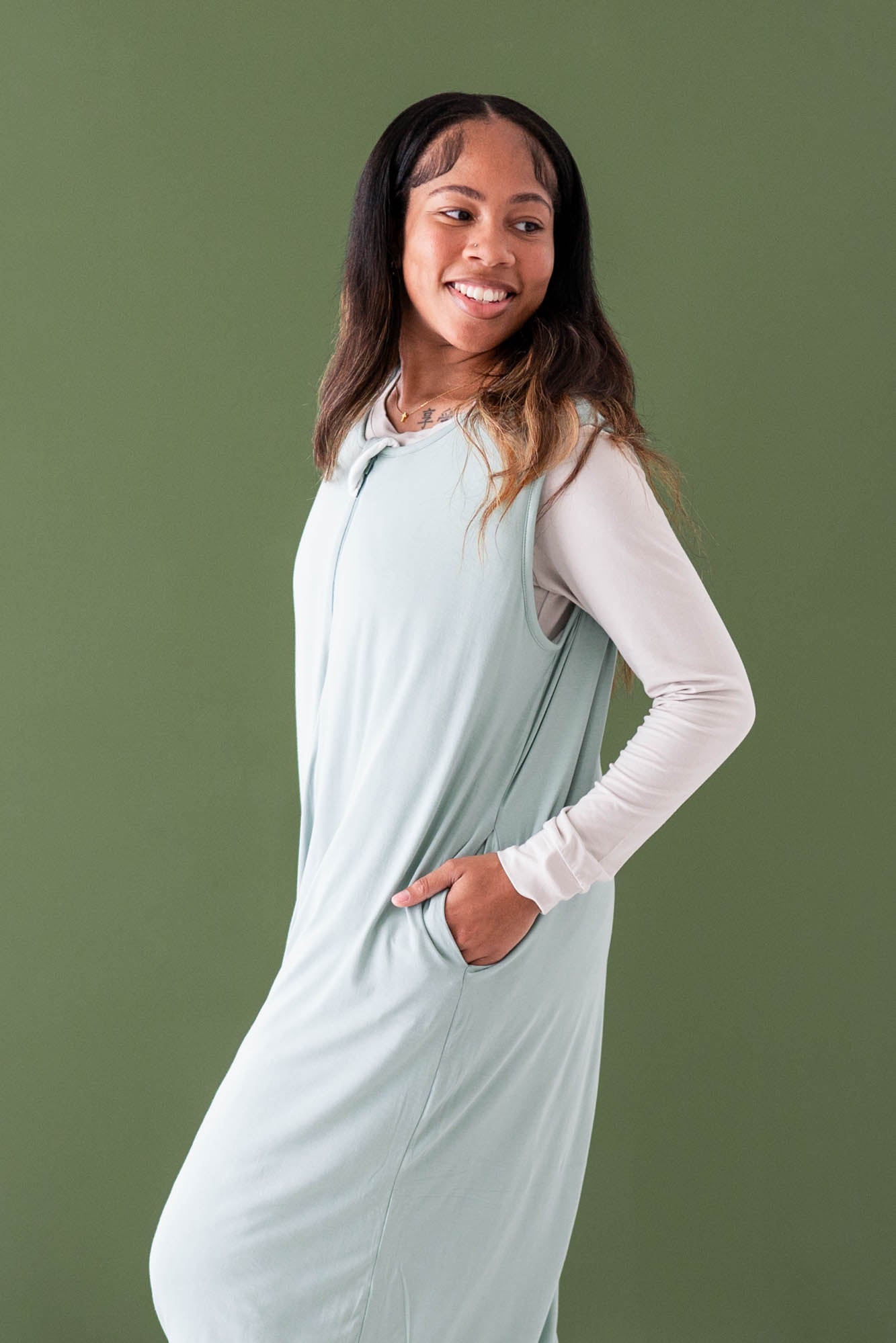 Closer up photo of female wearing the Adult Sleep Bag Walker in Sage with one hand in the pocket