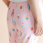 Model showcasing back of Pink Women's Lounge Pants in Ice Cream print under white camisole on beige background