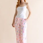 Model wearing Pink Women's Lounge Pants in Ice Cream print under white camisole on beige background