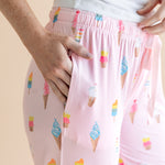 Model wearing Pink Women's Lounge Pants in Ice Cream print with pockets under white camisole on beige background