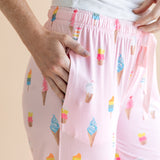 Model wearing Pink Women's Lounge Pants in Ice Cream print with pockets under white camisole on beige background