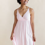 Woman wearing a light pink nightgown dress against a beige background