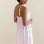 Woman wearing a light pink nightgown dress against a beige background