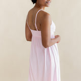 Woman wearing a light pink nightgown dress against a beige background