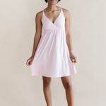 Woman wearing a light pink nightgown dress against a plain background