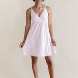 Woman wearing a light pink nightgown dress against a plain background