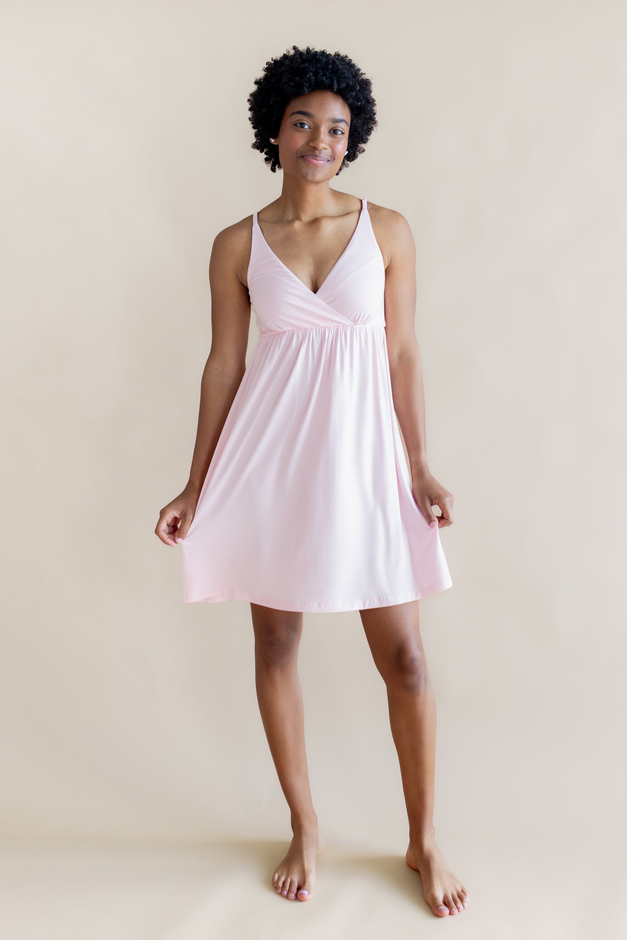 Woman wearing a light pink nightgown dress against a plain background