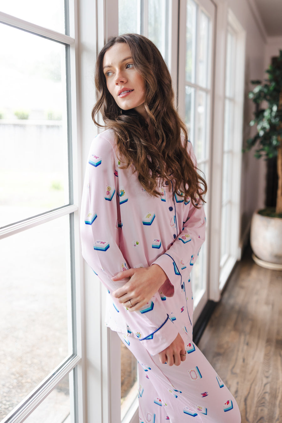 Modal wearing Long-Sleeved Women's Pajama Set in Sakura Mahjong print standing against a window in a living room