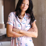 woman wearing pink short sleeve pajama set with mahjong tile print standing in a living room