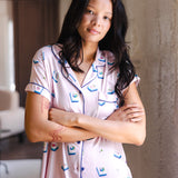 woman wearing pink short sleeve pajama set with mahjong tile print standing in a living room