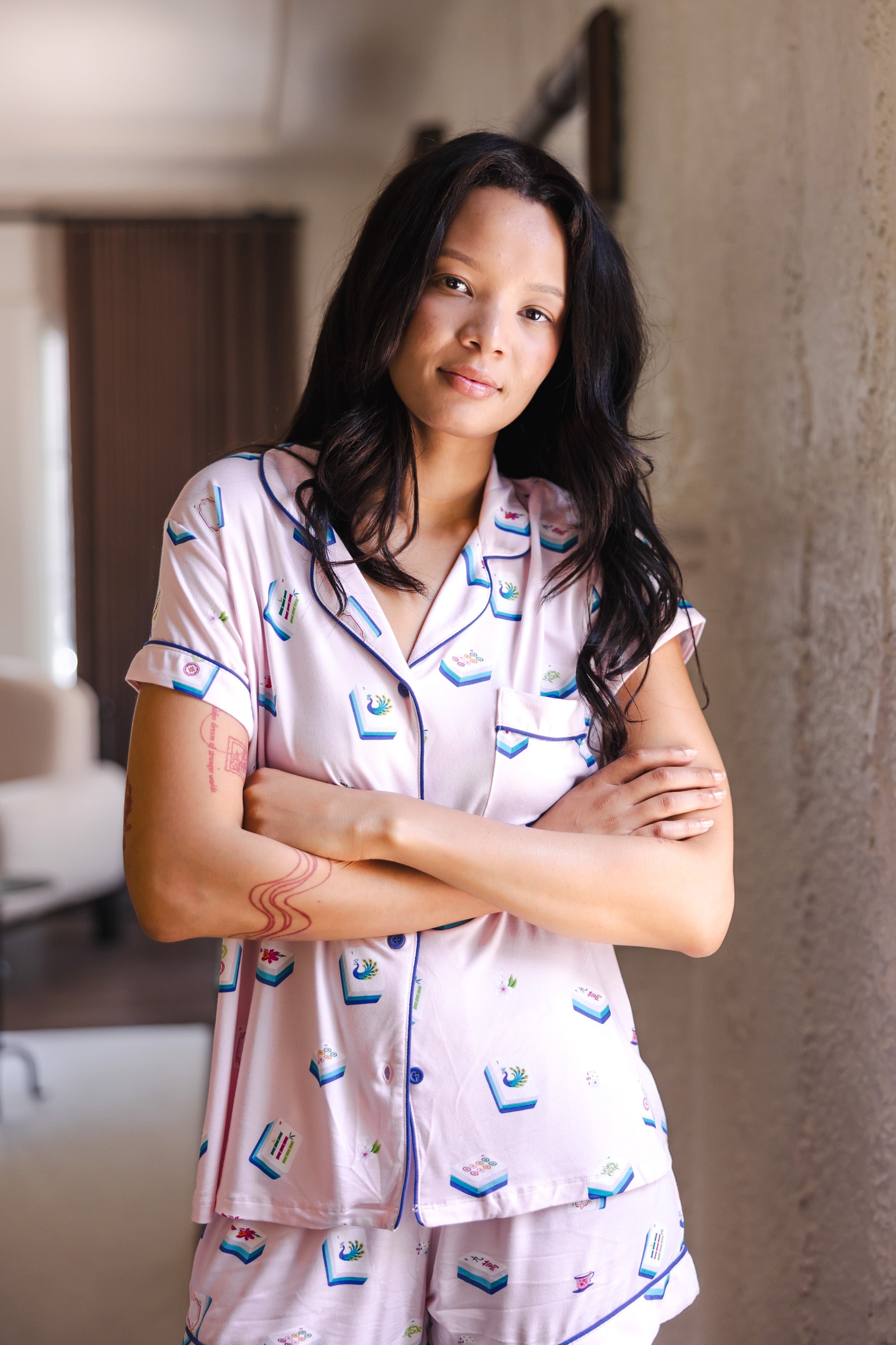 woman wearing pink short sleeve pajama set with mahjong tile print standing in a living room