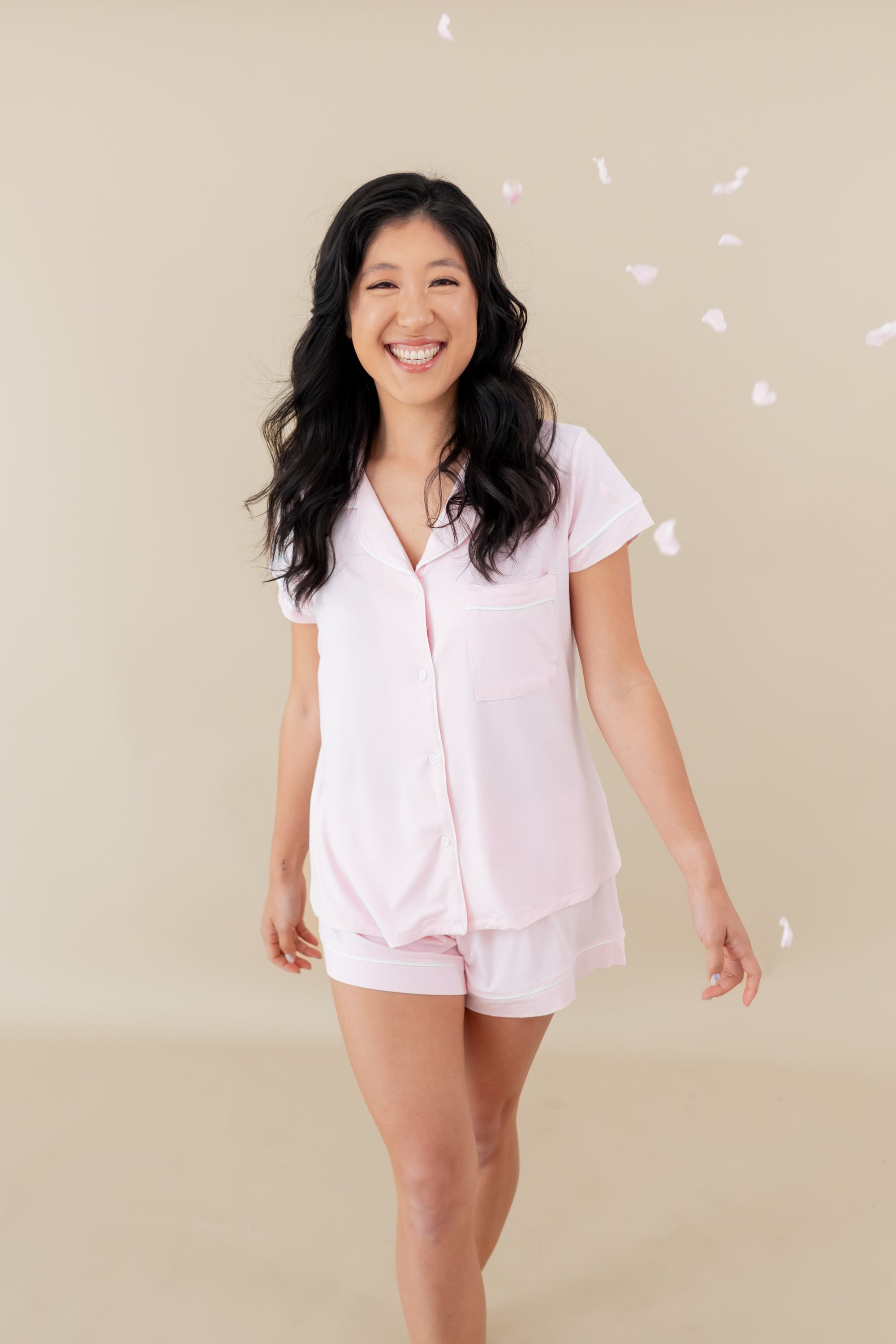 Woman modeling Women’s Short Sleeve Pajama Set in Sakura with Cloud Trim with falling petals
