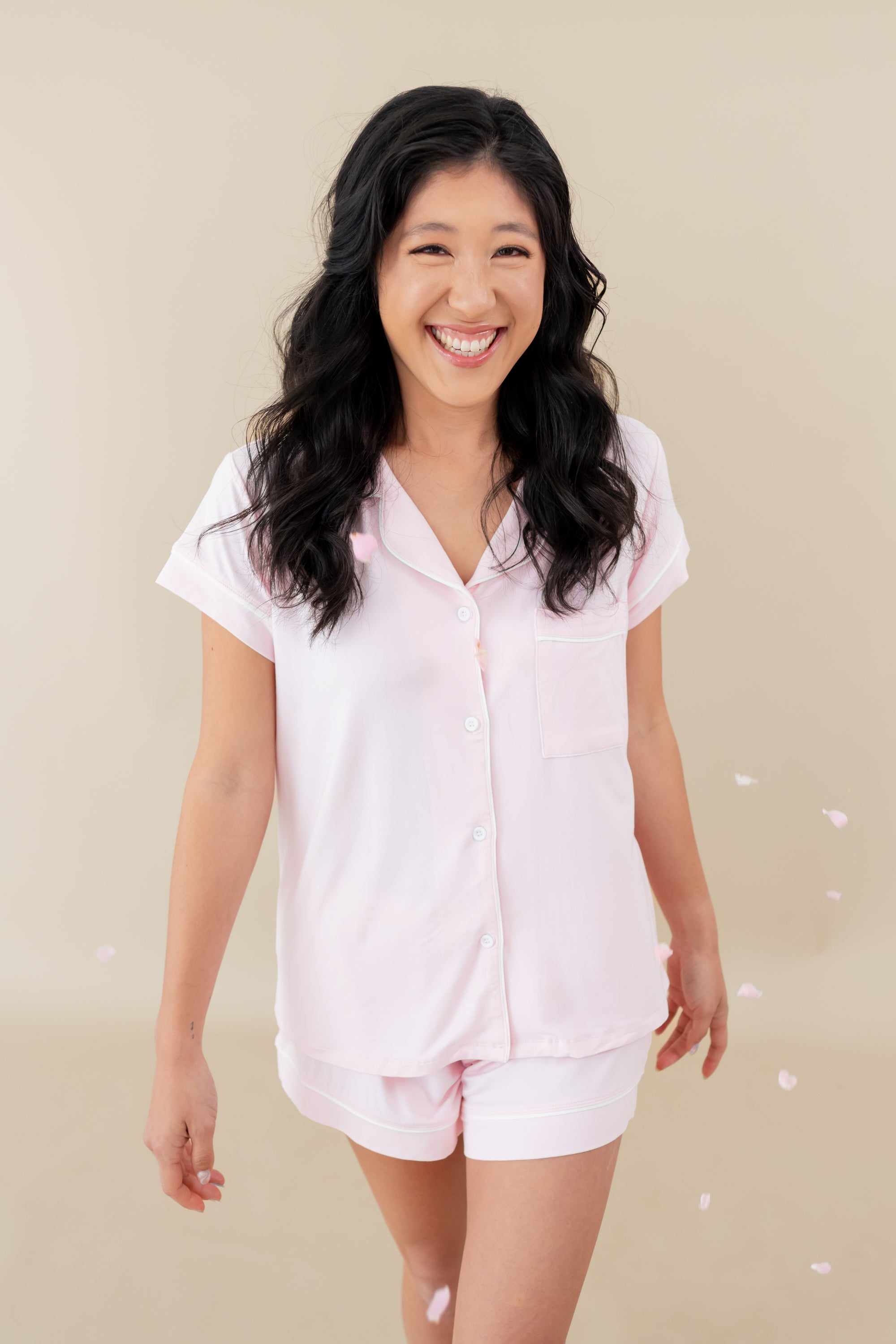 woman modeling Women’s Short Sleeve Pajama Set in Sakura with Cloud Trim with flower petals falling