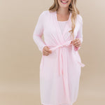 Smiling model holds the extra fabric of the waist tie on the tied up Women’s Lounge Robe in Sakura