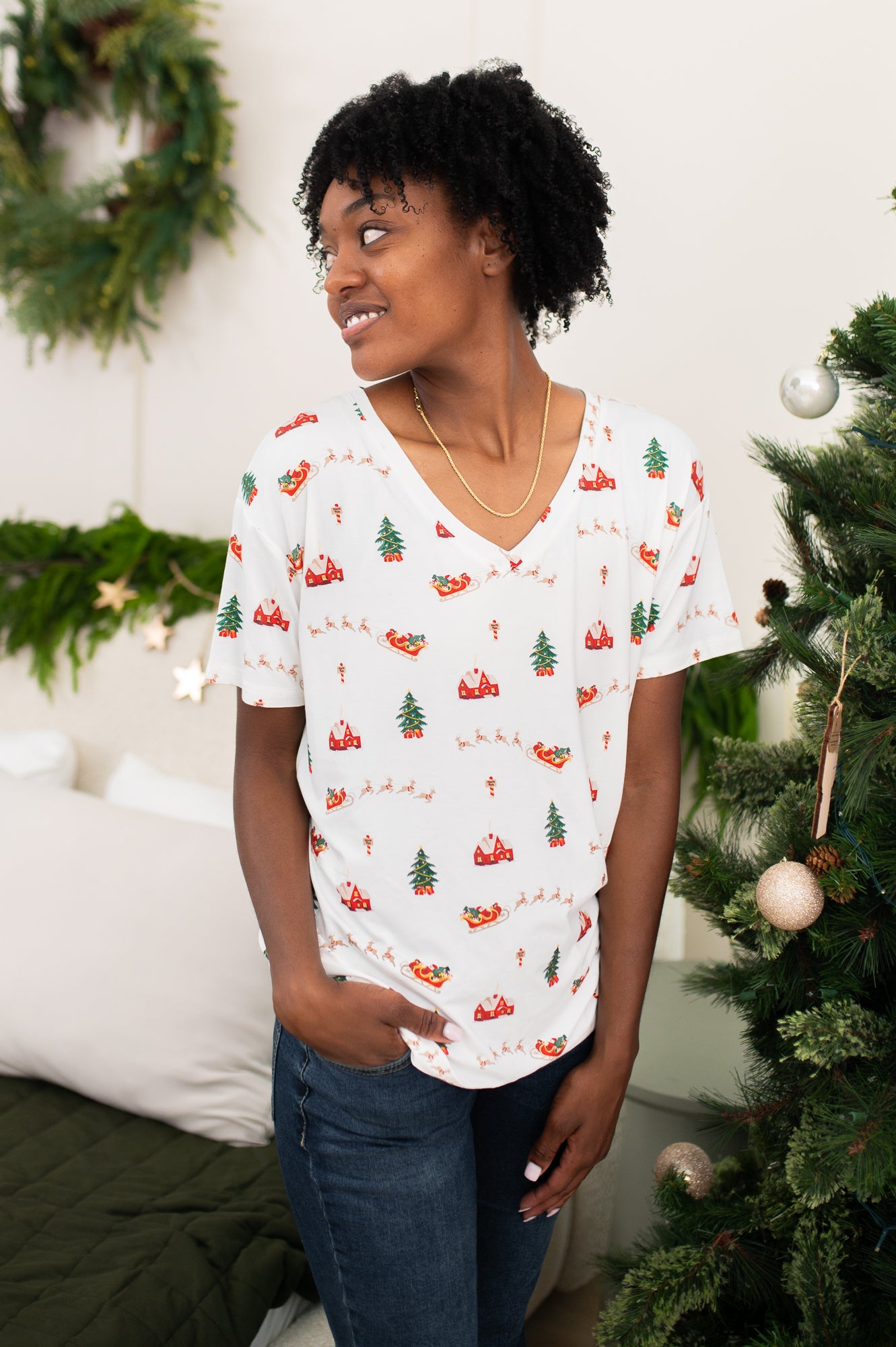 Model looking to the side while wearing the Women's Relaxed Fit V-Neck in Santa Sleigh paired with dark jeans