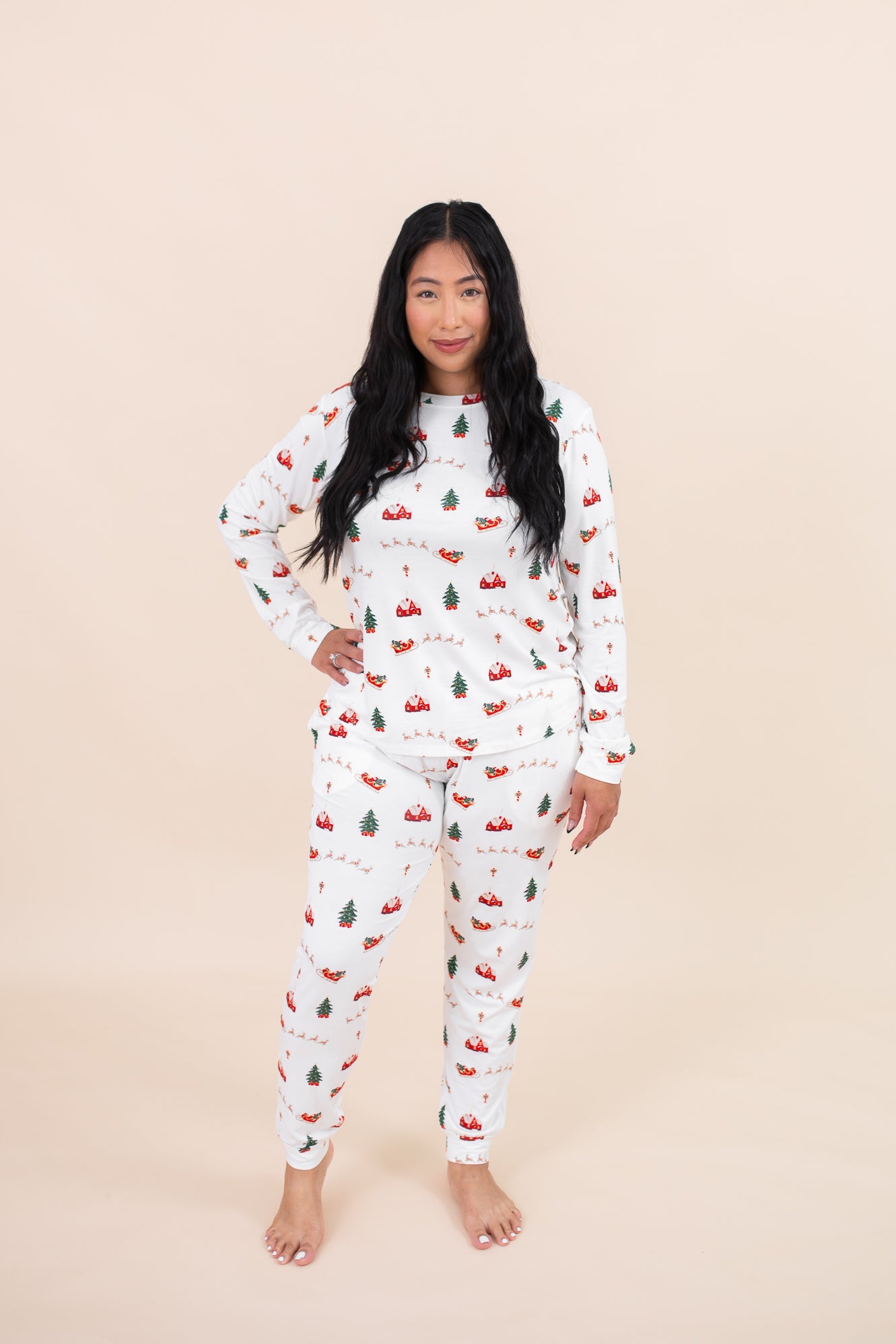 Smiling model wearing the Kyte Women's Jogger Pajama Set in Santa Sleigh