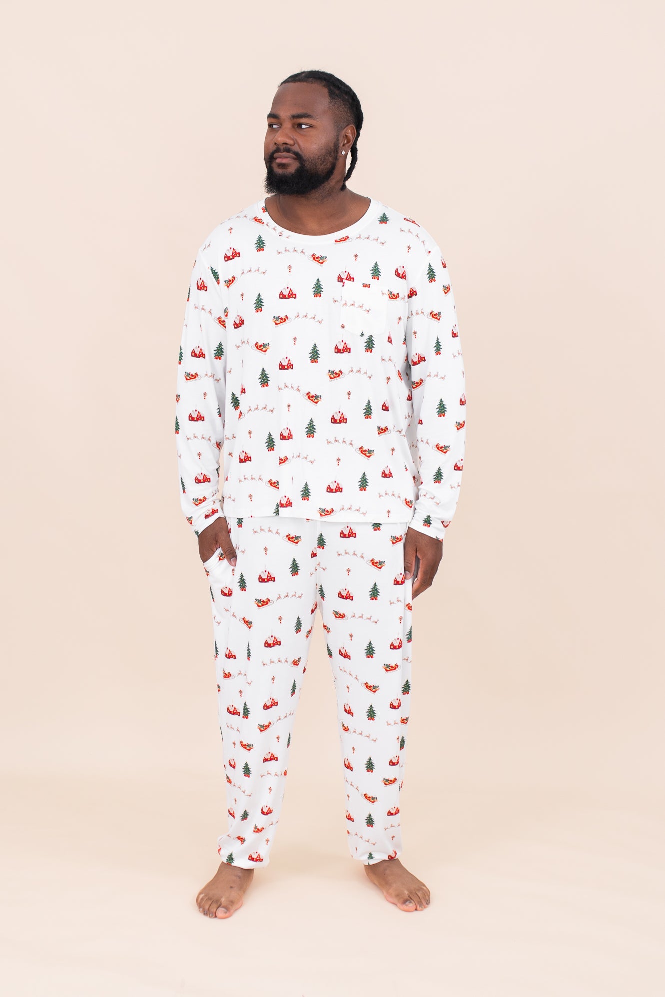 Man standing in front of a beige wall while modeling the Kyte Men's Jogger Set in Santa Sleigh