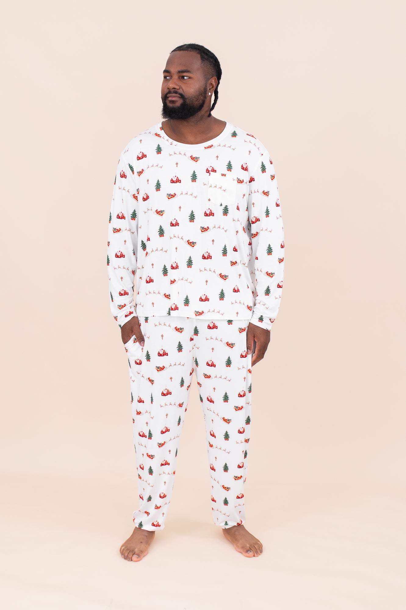 Man standing in front of a beige wall while modeling the Kyte Men's Jogger Set in Santa Sleigh
