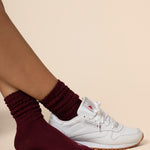 White sneakers with maroon socks on a beige background