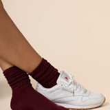 White sneakers with maroon socks on a beige background