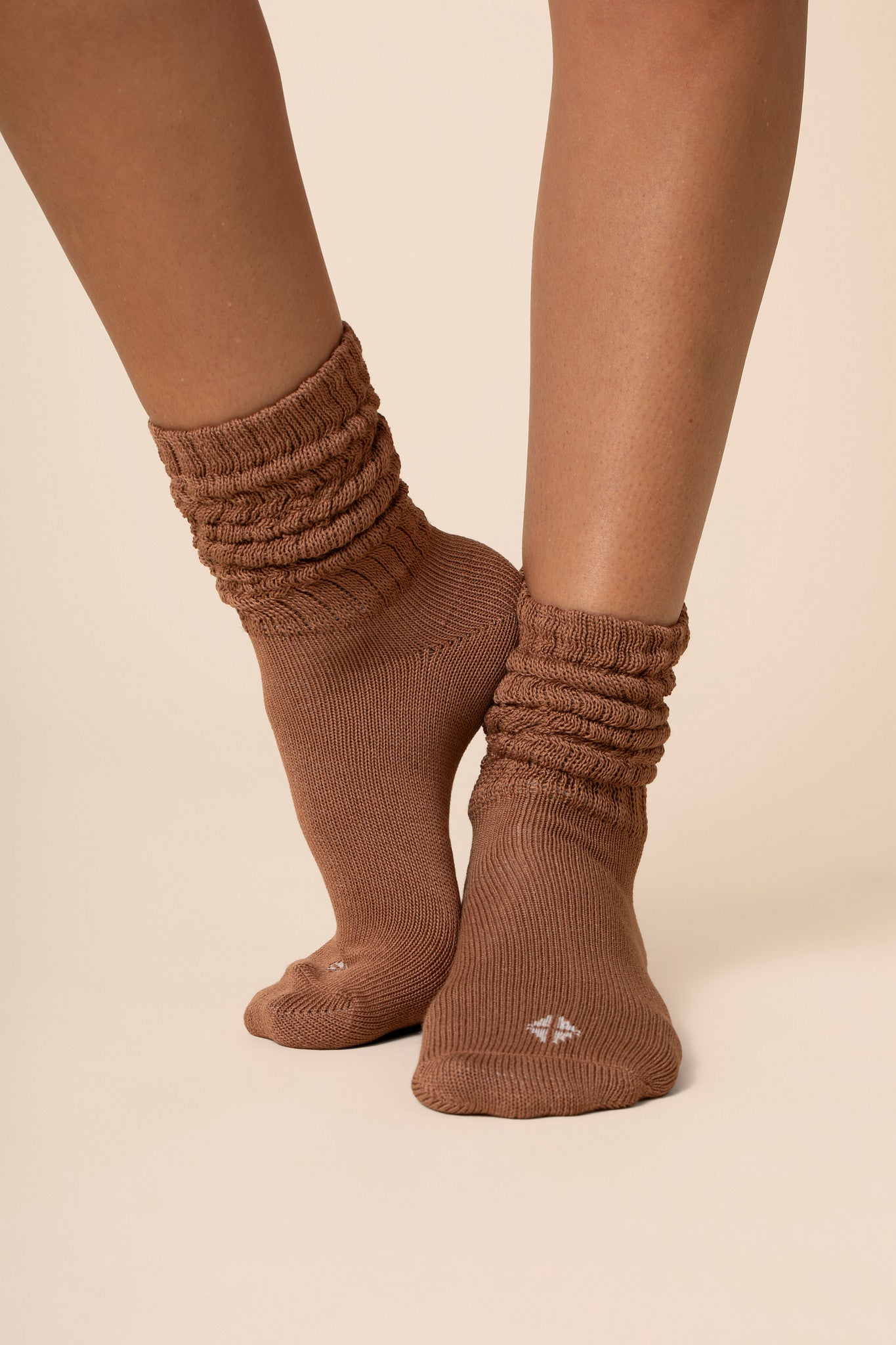 Brown scrunch socks worn by a person on a beige background