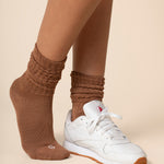Brown scrunch socks worn by a person on a beige background
