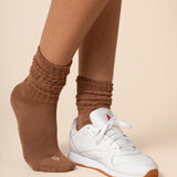 Brown scrunch socks worn by a person on a beige background