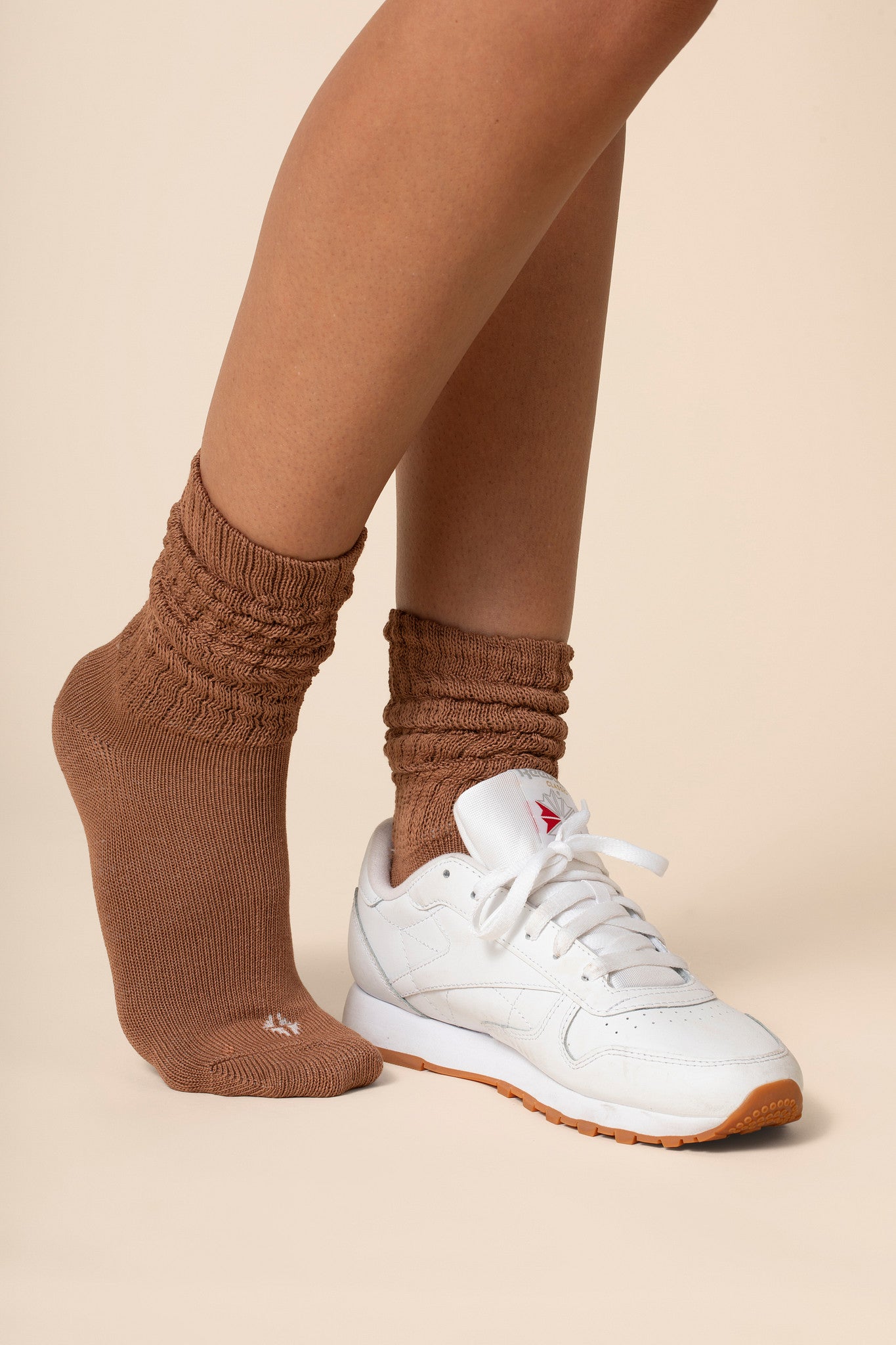 Brown scrunch socks worn by a person on a beige background