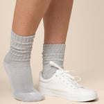 Gray socks worn with white sneakers on a beige background