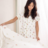 Model looking down fixing Sateen Sheets in Wildflower while wearing matching short sleeve pajama set