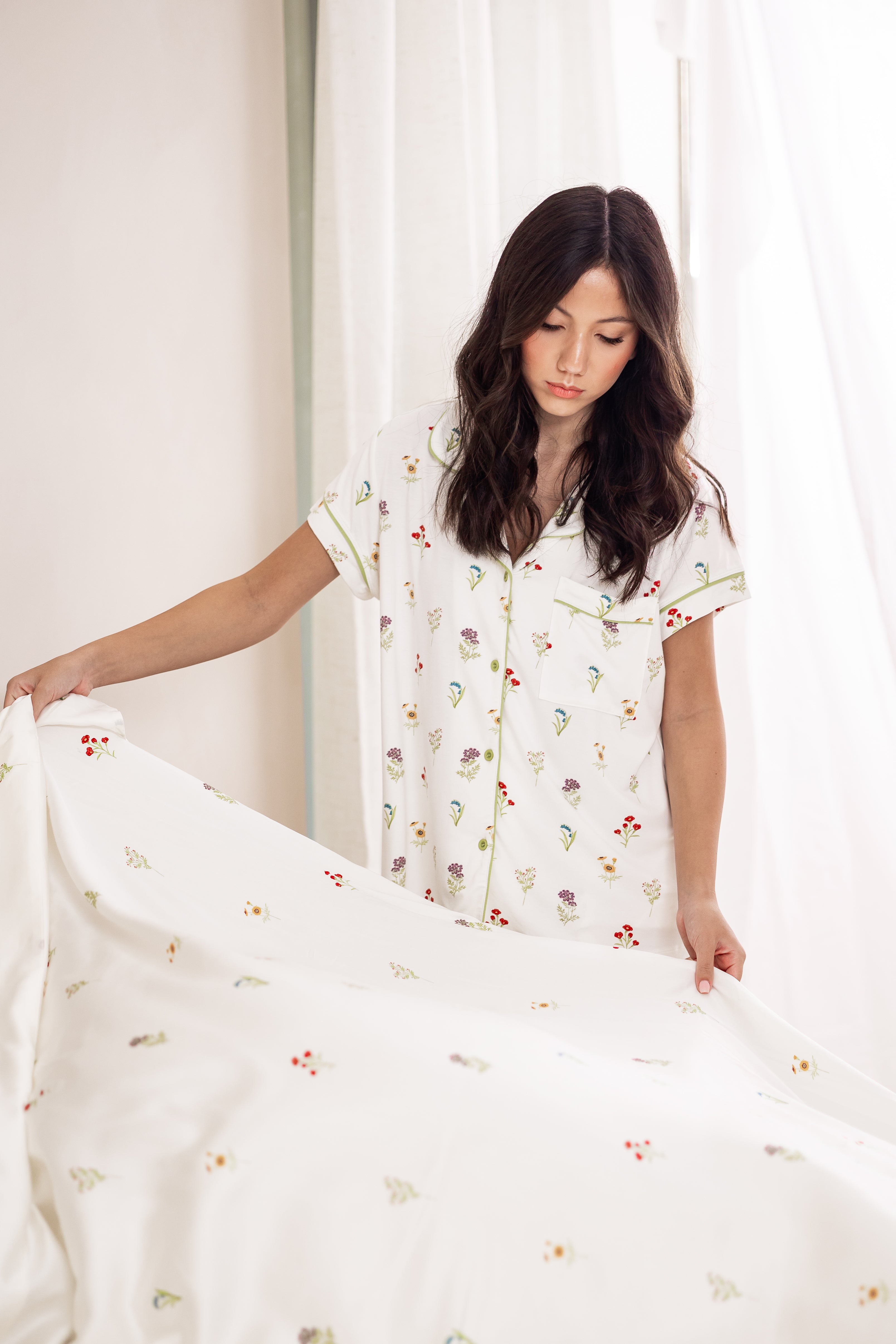Model looking down fixing Sateen Sheets in Wildflower while wearing matching short sleeve pajama set