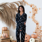 Smiling model in front of a Fall backdrop wearing the Long Sleeve Pajama Set in Skeleton 