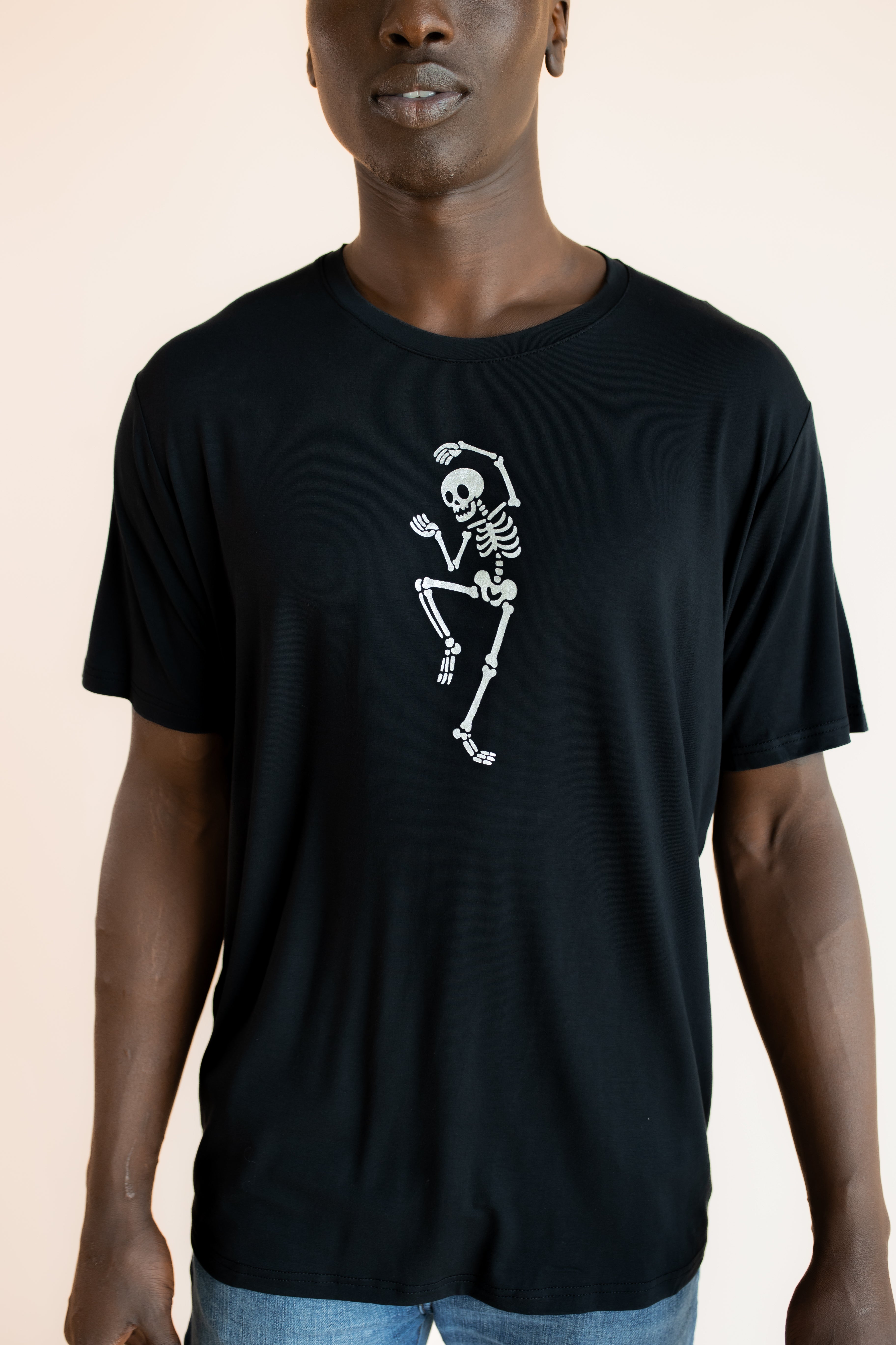 Close up of Modal wearing Black Men's Crew Neck Tee with Skeleton print in center on a beige background